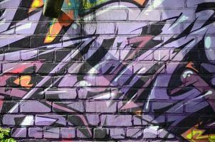 Fragment of graffiti drawings. The old wall decorated with paint stains in the style of street art culture. Colored background texture in purple tones photo