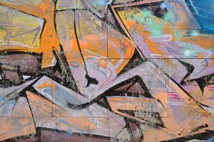Fragment of graffiti drawings. The old wall decorated with paint stains in the style of street art culture. Colored background texture in warm tones photo