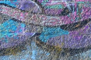 Fragment of graffiti drawings. The old wall decorated with paint stains in the style of street art culture. Colored background texture in purple tones photo