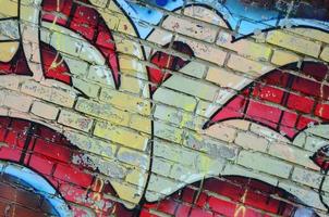 Fragment of graffiti drawings. The old wall decorated with paint stains in the style of street art culture. Colored background texture in warm tones photo