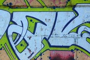Fragment of graffiti drawings. The old wall decorated with paint stains in the style of street art culture. Colored background texture in green tones photo