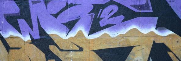 Fragment of graffiti drawings. The old wall decorated with paint stains in the style of street art culture. Colored background texture in purple tones photo