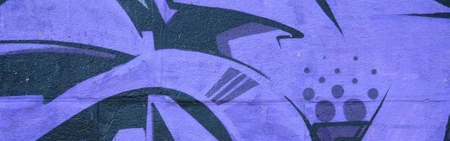 Fragment of graffiti drawings. The old wall decorated with paint stains in the style of street art culture. Colored background texture in purple tones photo