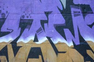 Fragment of graffiti drawings. The old wall decorated with paint stains in the style of street art culture. Colored background texture in purple tones photo