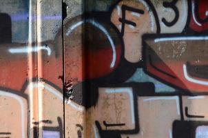 fragmento de dibujos de graffiti. la antigua muralla decorada con manchas de pintura al estilo de la cultura del arte callejero. textura de fondo coloreada en tonos cálidos foto