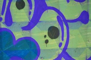 Fragment of an old colored graffiti drawing on the wall. Background image as an illustration of street art, vandalism and wall painting with aerosol paint photo