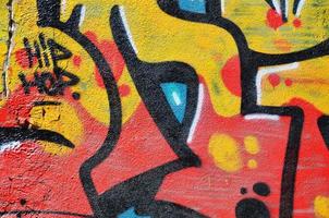 Fragment of an old colored graffiti drawing on the wall. Background image as an illustration of street art, vandalism and wall painting with aerosol paint photo