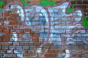 Fragment of an old colored graffiti drawing on the wall. Background image as an illustration of street art, vandalism and wall painting with aerosol paint photo