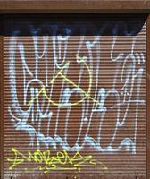 Fragment of an old colored graffiti drawing on the shutter door. Background image as an illustration of street art, vandalism and wall painting with aerosol paint photo