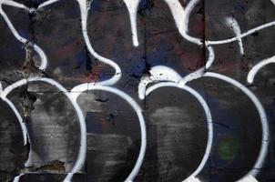 un fragmento de dibujo de graffiti utilizando contornos, aplicado a la pared con la ayuda de latas con pinturas en aerosol sobre las áreas de relleno coloreadas. textura de fondo de arte callejero y vandalismo foto