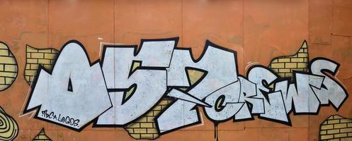 A photograph of a detailed wall artwork. Graffiti drawing is made with white paint with black outlines and has a monophonic orange background. Texture of wall with graffiti decoration photo