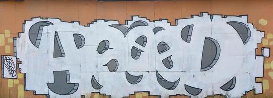 A photograph of a detailed wall artwork. Graffiti drawing is made with white paint with black outlines and has a monophonic orange background. Texture of wall with graffiti decoration photo