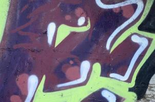 Fragment of graffiti drawings. The old wall decorated with paint stains in the style of street art culture. Colored background texture photo