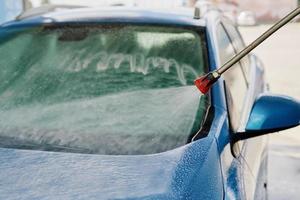 Cleaning car with high pressure water at car wash station photo