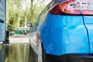 Cleaning car with high pressure water at car wash station photo