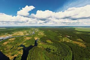 Blue cloudy sky ove river floodplain landscape and green forest, aerial view photo
