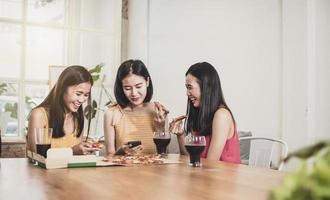 group of Asian funny women enjoying eating food and playing phone at home