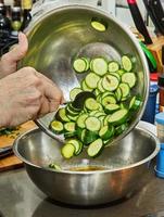 Chef pours zucchini into salad bowl in the kitchen photo