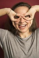 Portrait of emotional positive European teenage girl wearing her light hair in bun, shouting in amazement or astonishment keeping hands on face photo