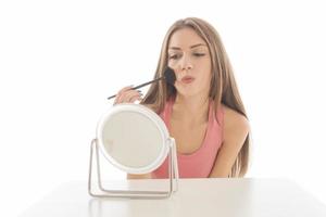 hermosa mujer sentada frente a un espejo. cara de una mujer sana aplicando crema y maquillaje. anuncio de crema para la piel, crema antiarrugas, cara de bebé foto