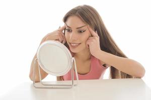 Beautiful woman sitting in front of a mirror. face of a healthy woman applying cream and makeup. Advertisement for skin cream, anti-wrinkle cream, baby face photo