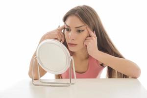 Beautiful woman sitting in front of a mirror. face of a healthy woman applying cream and makeup. Advertisement for skin cream, anti-wrinkle cream, baby face photo