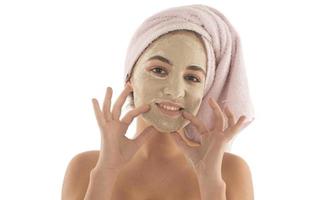 Beauty procedures skin care concept. Young woman applying facial mud clay mask to her face photo