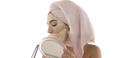 Beauty procedures skin care concept. Young woman applying facial mud clay mask to her face photo