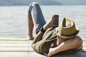 young man on pear by a lake at a sunny day relaxing. photo