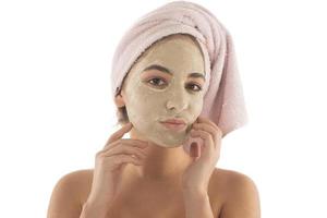 Beauty procedures skin care concept. Young woman applying facial mud clay mask to her face photo