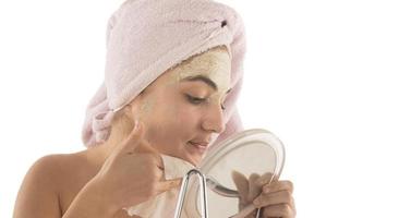 Beauty procedures skin care concept. Young woman applying facial mud clay mask to her face photo