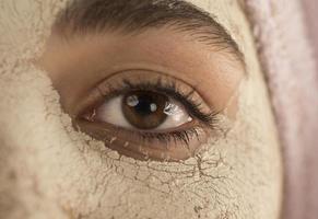 Beauty procedures skin care concept. Young woman applying facial mud clay mask to her face photo