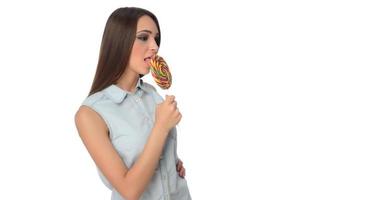 woman licking sweet candy. Female model eating delicious confectionery lollipop with surprised expression. studio shot isolated white background photo