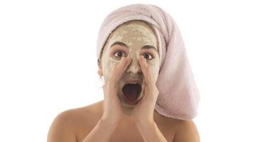 Beauty procedures skin care concept. Young woman applying facial mud clay mask to her face photo