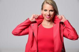 mujer sonriente rubia de moda con accesorios modernos posando en el estudio foto