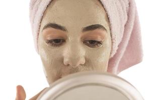 Beauty procedures skin care concept. Young woman applying facial mud clay mask to her face photo