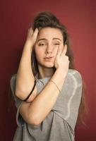 Portrait of emotional positive European teenage girl wearing her light hair in bun, shouting in amazement or astonishment keeping hands on face photo