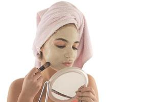 Beauty procedures skin care concept. Young woman applying facial mud clay mask to her face photo