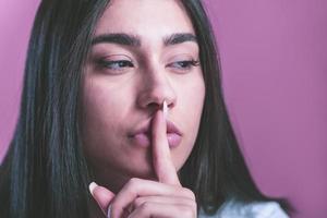 Photo of the creative expression of the silent woman. Brunette woman doing shhh sign