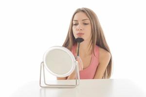 hermosa mujer sentada frente a un espejo. cara de una mujer sana aplicando crema y maquillaje. anuncio de crema para la piel, crema antiarrugas, cara de bebé foto