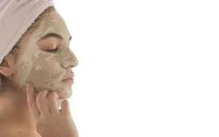 procedimientos de belleza concepto de cuidado de la piel. mujer joven aplicando máscara de arcilla de barro facial a su cara foto