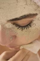 Beauty procedures skin care concept. Young woman applying facial mud clay mask to her face photo