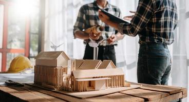 Scale model house on table with architects. Two architects making architectural model in office together. to form a new buildin photo
