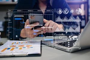 Businessman hand Project manager working and update tasks and Gantt chart scheduling virtual diagram.with smart phone, tablet and laptop in office. photo