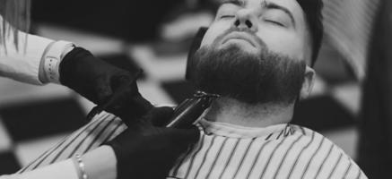 Barber cutting beard of male client photo