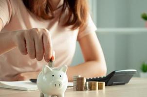 las mujeres están poniendo monedas en una alcancía para un negocio que crece con fines de lucro y ahorra dinero para el futuro. planificación para el concepto de jubilación foto