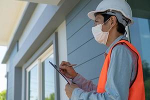 Inspectors or engineers are wearing an anti-virus mask and checking the building structure and the requirements of the wall paint. After the renovation is completed