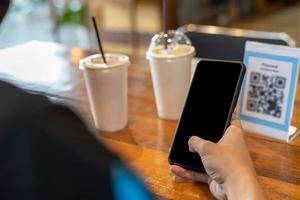 el hombre usa un teléfono inteligente para escanear el código qr para pagar en un café restaurante con un pago digital sin efectivo. elige menú y ordena acumula descuento. billetera electrónica, tecnología, pago en línea, tarjeta de crédito, aplicación bancaria foto