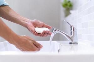 Men washing hands with soap and clean water in front of the bathroom sink to prevent the spread of germs. Washing hands with soap.