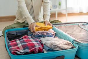 bolsas de viaje para viajes de vacaciones. una joven prepara ropa y artículos personales para poner en su maleta. hacer las maletas antes de viajar foto